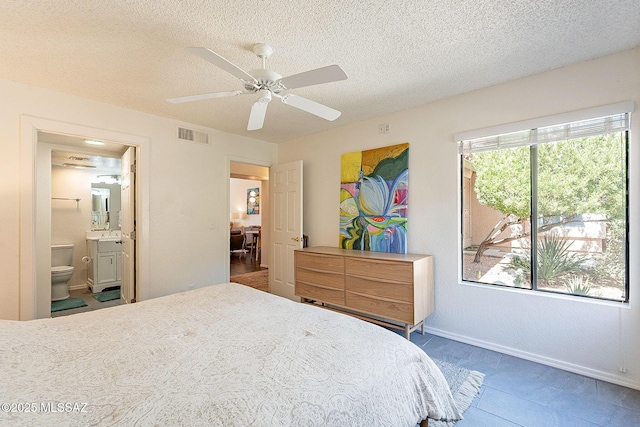 bedroom with a textured ceiling, a sink, visible vents, and connected bathroom