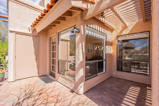 doorway to property with a pergola and stucco siding