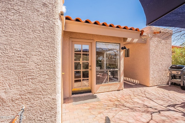 property entrance with a tile roof and stucco siding