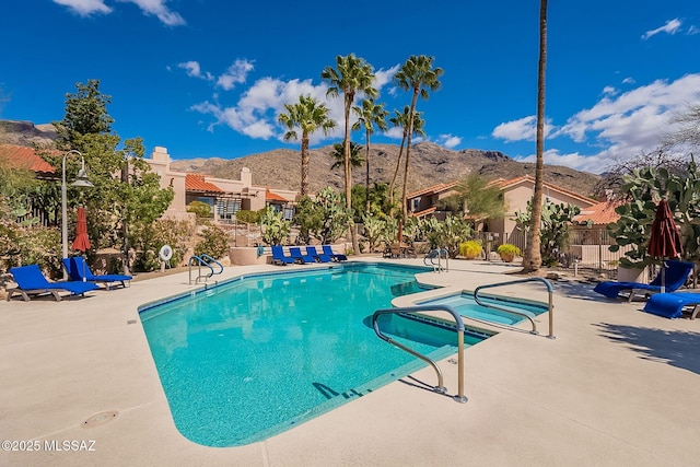 community pool with a mountain view, fence, and a patio