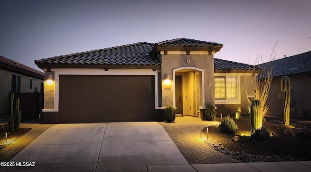 mediterranean / spanish home with a garage, concrete driveway, a tile roof, and stucco siding