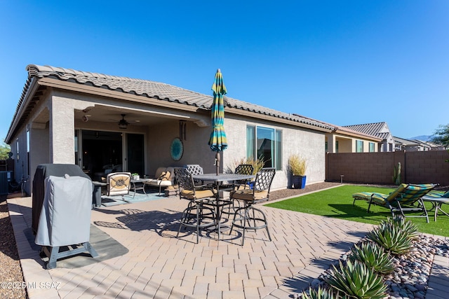 rear view of property featuring ceiling fan, a patio, fence, a tiled roof, and stucco siding