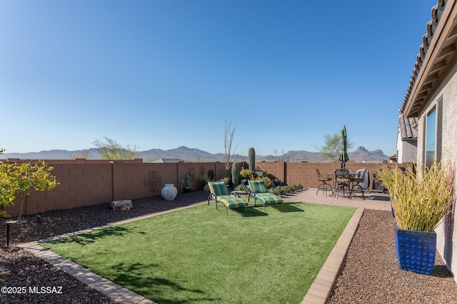 view of yard with a patio area, a fenced backyard, and a mountain view