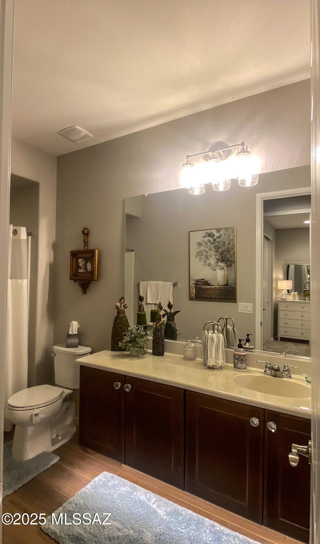 bathroom featuring visible vents, wood finished floors, vanity, and toilet