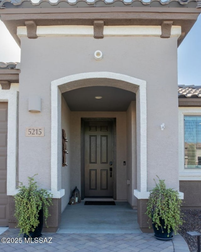 view of exterior entry featuring a tiled roof and stucco siding