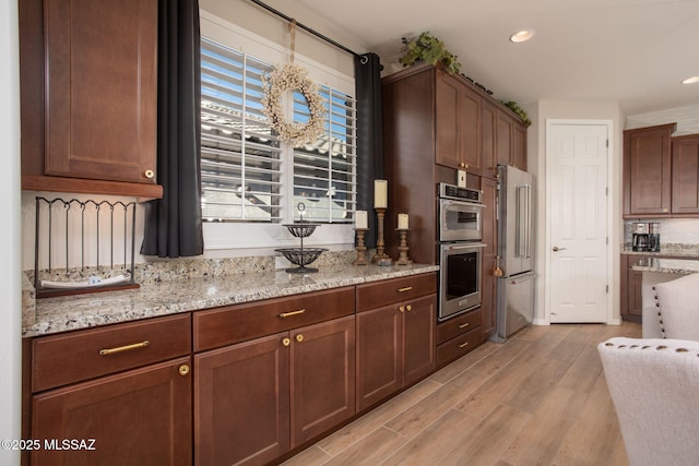 kitchen with light wood finished floors, appliances with stainless steel finishes, light stone counters, and recessed lighting