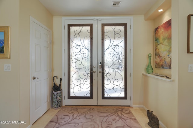 foyer entrance with light tile patterned flooring, visible vents, and french doors