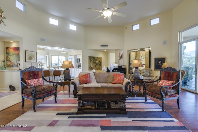 living area featuring ceiling fan, wood finished floors, visible vents, and a healthy amount of sunlight