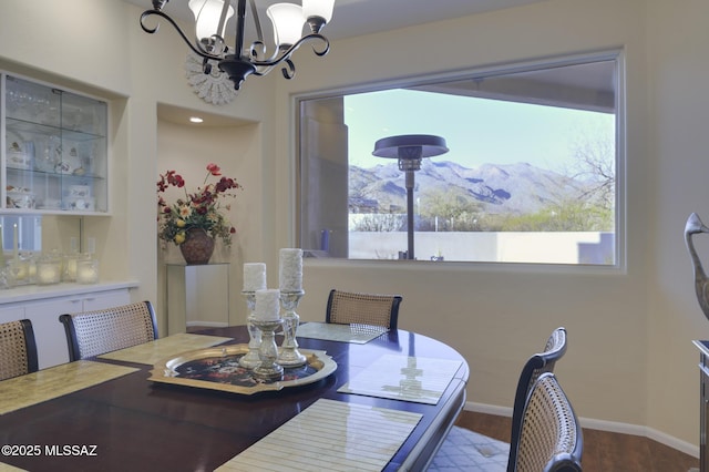 dining room featuring baseboards, wood finished floors, a mountain view, and a notable chandelier