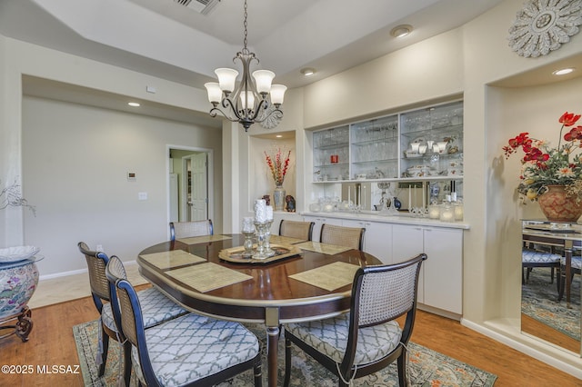 dining space with light wood-type flooring, visible vents, a notable chandelier, and baseboards