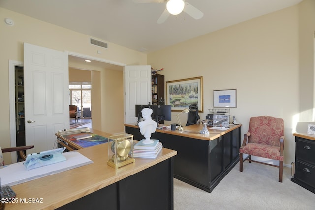 home office featuring a ceiling fan, visible vents, and light carpet