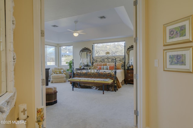 bedroom featuring ceiling fan, a raised ceiling, carpet flooring, and visible vents