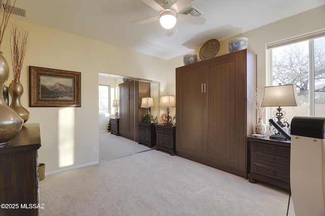 bedroom featuring baseboards, multiple windows, visible vents, and light colored carpet