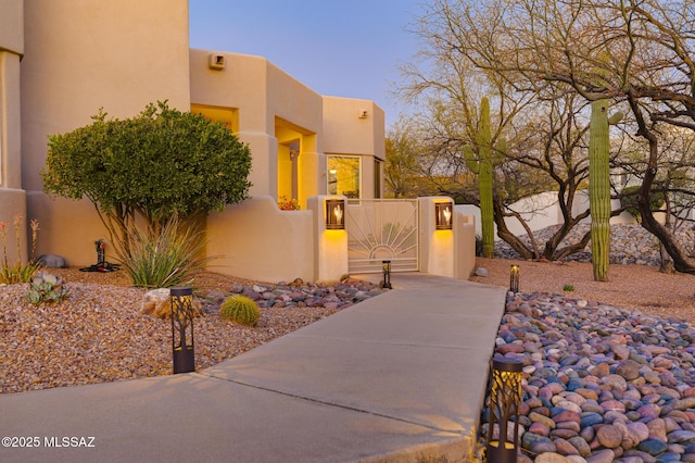 view of front of house featuring a gate, fence, and stucco siding