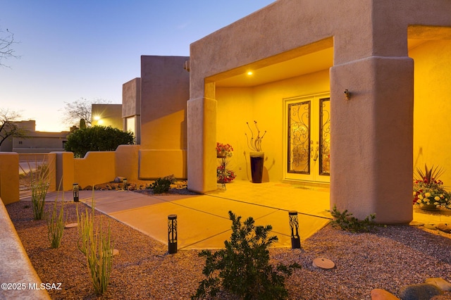 property exterior at dusk with french doors and stucco siding