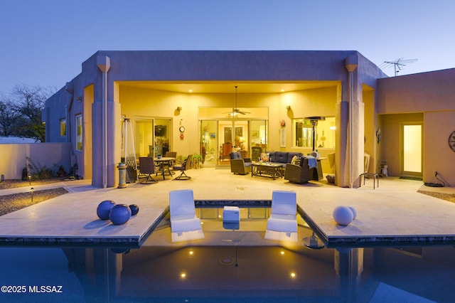 rear view of property with a fenced in pool, outdoor lounge area, a patio, and stucco siding