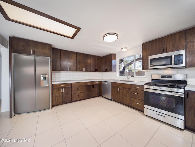 kitchen with stainless steel appliances, light countertops, dark brown cabinetry, and a sink