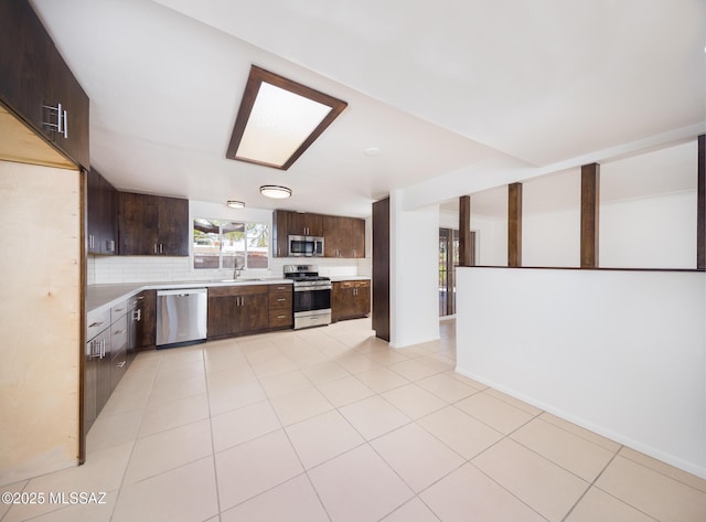 kitchen with a sink, stainless steel appliances, light countertops, and dark brown cabinetry