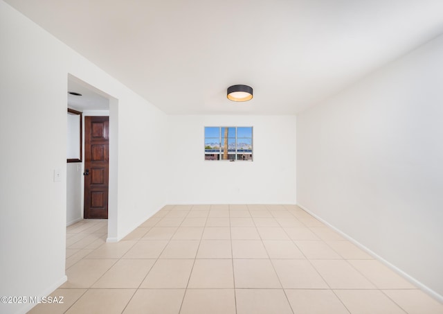 empty room featuring baseboards and light tile patterned floors