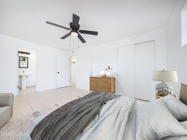 bedroom featuring light tile patterned floors, ceiling fan, connected bathroom, and a closet