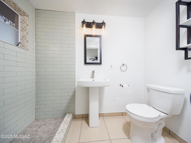 bathroom featuring tiled shower, tile patterned flooring, toilet, and baseboards