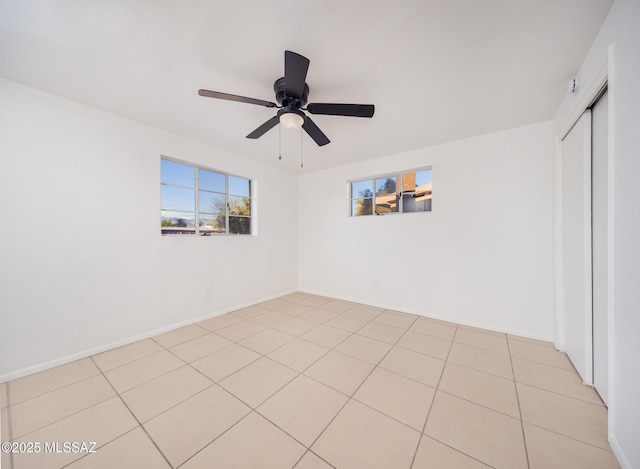 empty room with ceiling fan, baseboards, and light tile patterned flooring