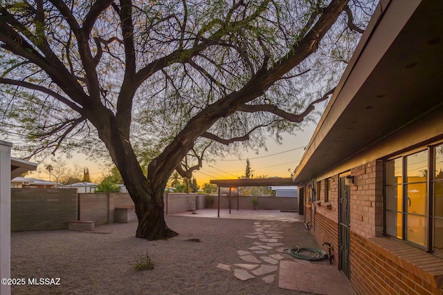 yard at dusk featuring a patio area and a fenced backyard