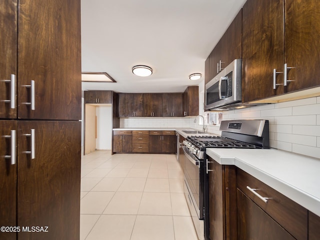 kitchen featuring stainless steel appliances, light countertops, dark brown cabinetry, and a sink