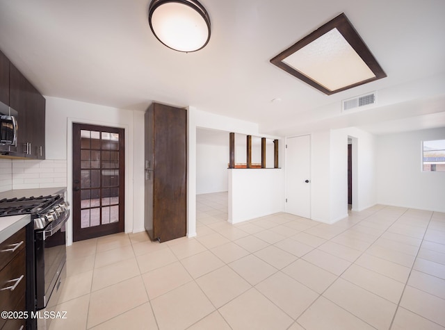 kitchen with dark brown cabinetry, visible vents, light countertops, backsplash, and gas range