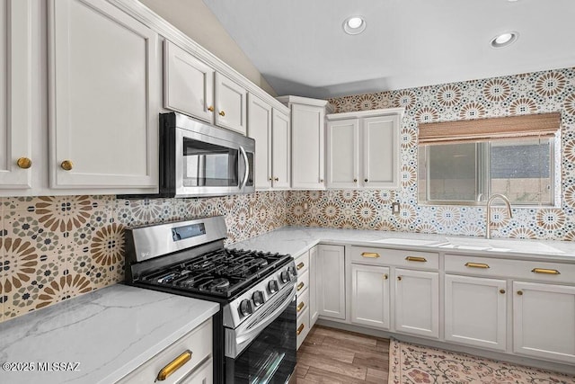 kitchen with vaulted ceiling, visible vents, wood finished floors, and ceiling fan with notable chandelier