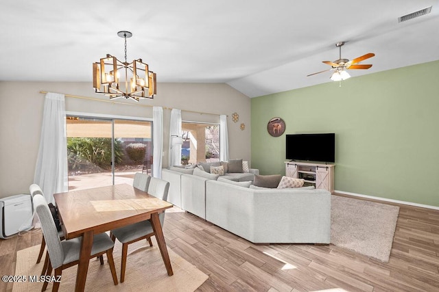 dining area featuring baseboards, vaulted ceiling, a chandelier, and light wood-type flooring