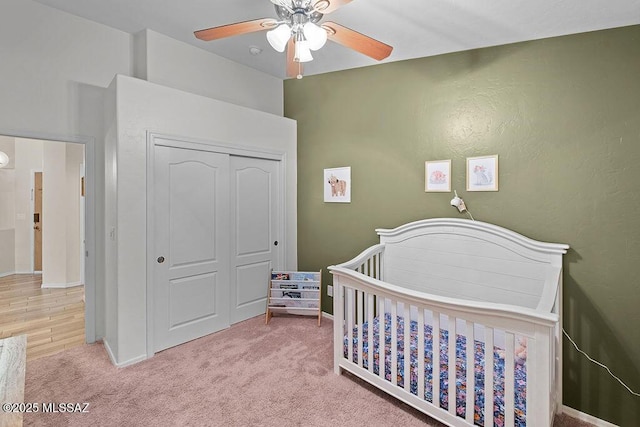 carpeted bedroom featuring a nursery area, lofted ceiling, a ceiling fan, and baseboards