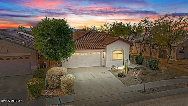 view of front of home with a garage, concrete driveway, a tiled roof, and stucco siding