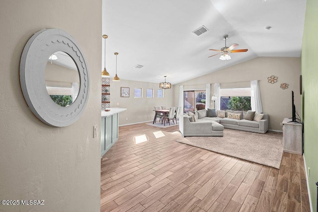 living area featuring ceiling fan with notable chandelier, vaulted ceiling, visible vents, and light wood finished floors