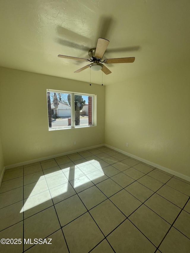 spare room featuring ceiling fan, baseboards, and light tile patterned floors