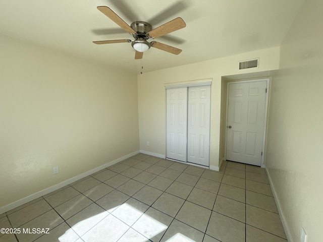 unfurnished bedroom with light tile patterned floors, a closet, visible vents, a ceiling fan, and baseboards