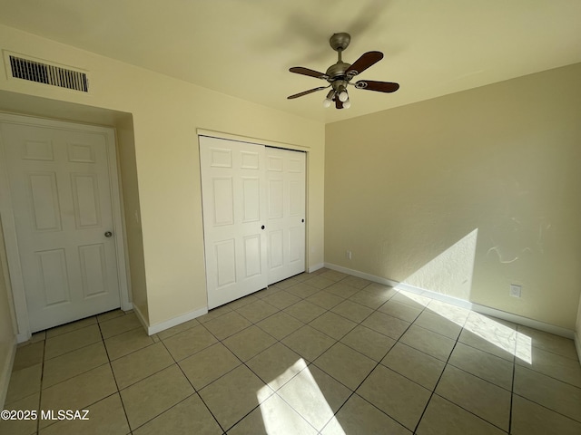 unfurnished bedroom featuring light tile patterned floors, a closet, visible vents, and baseboards