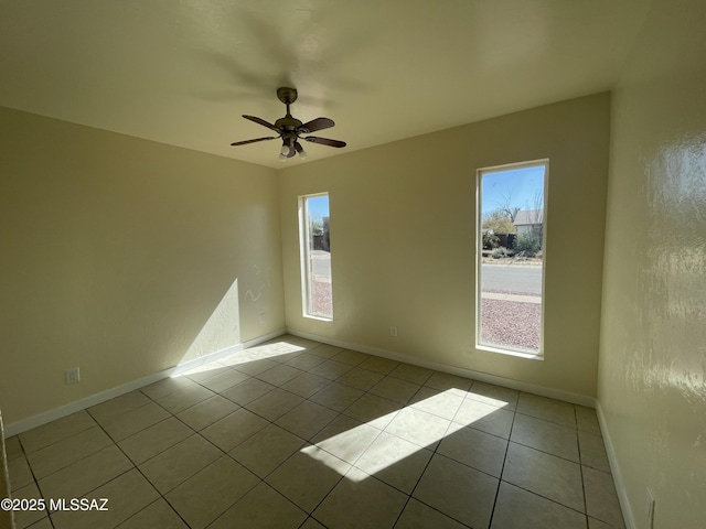 empty room featuring a ceiling fan, light tile patterned flooring, and baseboards