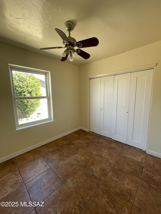 unfurnished bedroom featuring a textured ceiling, a closet, a ceiling fan, and baseboards