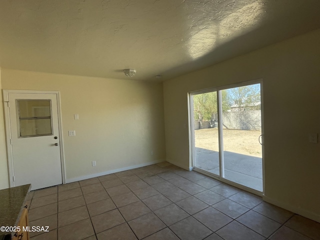 unfurnished room with a textured ceiling, baseboards, and light tile patterned floors