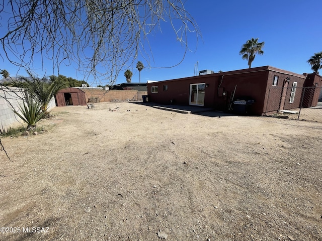 rear view of house featuring brick siding, fence, an outdoor structure, and a storage unit