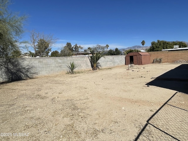 view of yard with a fenced backyard, a storage unit, and an outdoor structure