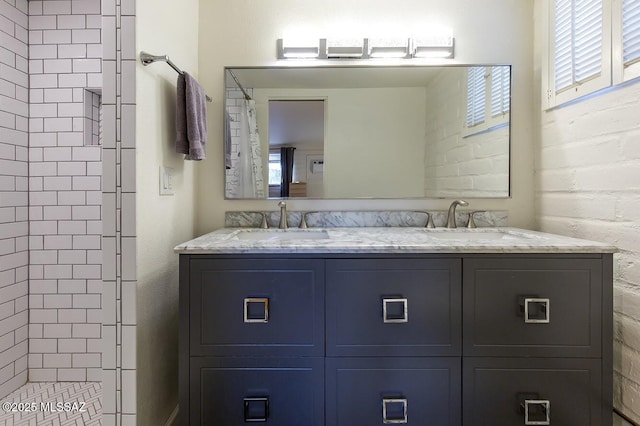 full bathroom featuring double vanity, a sink, and tiled shower