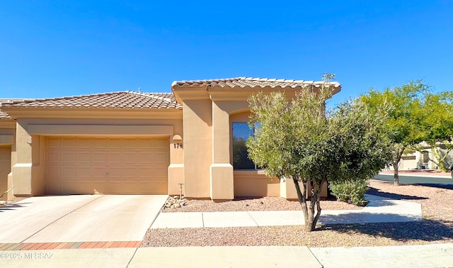 view of front of property featuring concrete driveway, a tile roof, an attached garage, and stucco siding