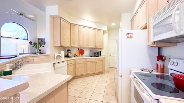 kitchen featuring white appliances, light countertops, a sink, and light brown cabinetry