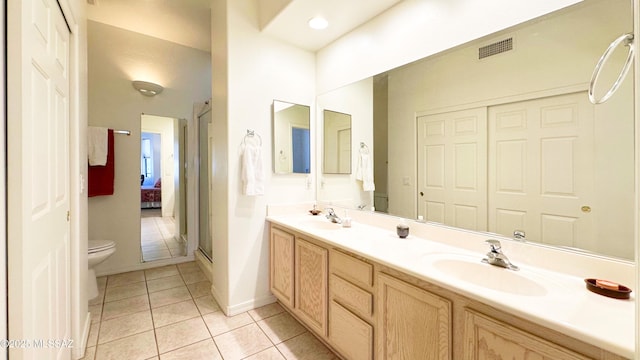 ensuite bathroom with double vanity, visible vents, toilet, tile patterned floors, and a sink