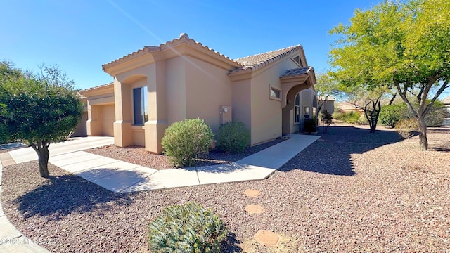 view of home's exterior featuring a garage, central AC unit, a tile roof, and stucco siding