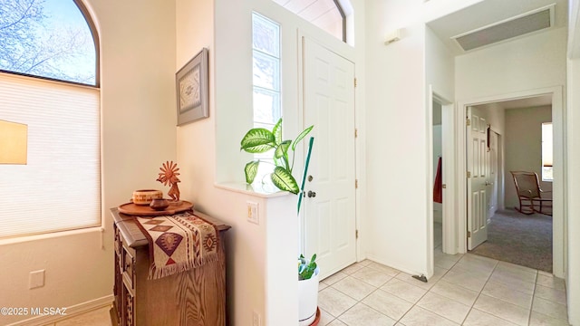 foyer entrance with light tile patterned flooring, visible vents, and baseboards