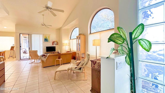 living area with high vaulted ceiling, light tile patterned flooring, plenty of natural light, and a ceiling fan