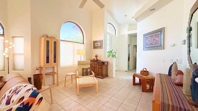 sitting room with a ceiling fan, a towering ceiling, and light tile patterned floors